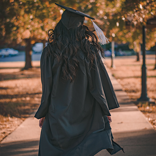 opporteunities pexels-stanley-morales-3186386 A photo of a girl with her back to the camera, in a graduation gown walking in a park.